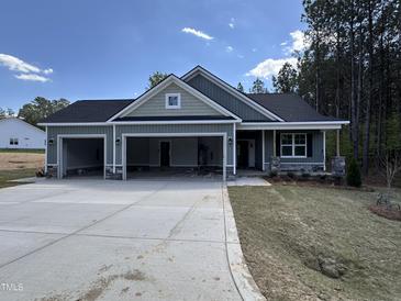 New construction home with three-car garage, black roof, light-green siding, and stone accents at 139 Red River Dr, Selma, NC 27576