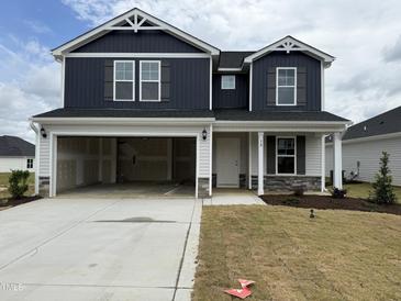 Two-story home boasts a dark blue facade, open garage and manicured front lawn at 18 W Emily Gardens Dr, Selma, NC 27576