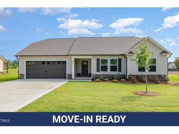 Charming single-story home with a well-manicured lawn, attached garage and appealing neutral color palette at 210 Maxwell Farm Ln, Selma, NC 27576