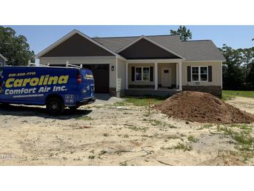 Inviting single-Gathering home featuring a partial stone facade, covered porch, and attached garage at 28 Bailey-Boykin Rd, Selma, NC 27576