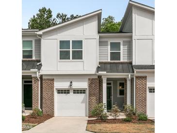 Charming townhome exterior featuring a brick facade, garage, and well-maintained landscaping at 309 Millennium Dr, Pittsboro, NC 27312