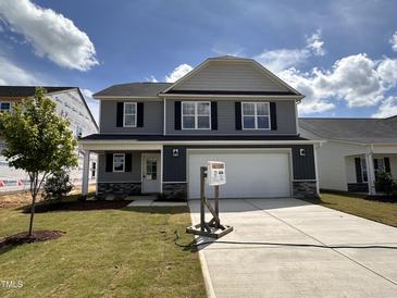 Charming two-story home with a two-car garage, landscaped lawn and stone accents on the facade at 33 W Emily Gardens Dr, Selma, NC 27576