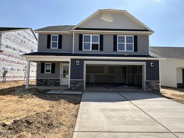 New two-story home with a two-car garage and stone-accented facade, awaiting landscaping at 33 W Emily Gardens Dr, Selma, NC 27576