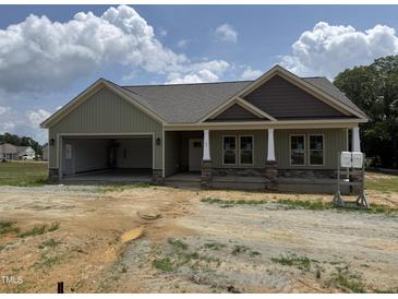 A charming one-story home with a light green exterior, covered porch, and an attached two-car garage at 56 Bailey-Boykin Rd, Selma, NC 27576