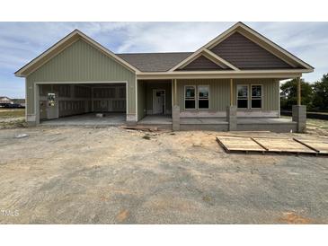 Charming exterior view of a single-story home with an attached two-car garage on a partly cloudy day at 56 Bailey-Boykin Rd, Selma, NC 27576