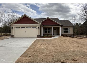 Charming single-story home with a two-car garage, red accents, and a freshly seeded yard at 702 Tuscany Cir, Princeton, NC 27569