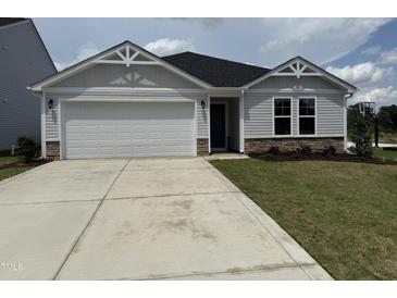 Charming single-story home featuring a two-car garage and well-maintained lawn at 8 W Emily Gardens Dr, Selma, NC 27576
