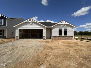 Charming single-story home with stone accents, gray siding, an attached two-car garage and unfinished yard at 8 W Emily Gardens Dr, Selma, NC 27577
