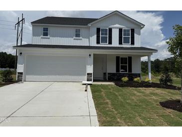Charming two-story home with a two-car garage, beautiful landscaping, and a welcoming front porch at 82 W Emily Gardens Dr, Selma, NC 27576