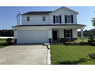 Charming two-story home with a two-car garage, manicured lawn, and stone accents at 82 W Emily Gardens Dr, Selma, NC 27576