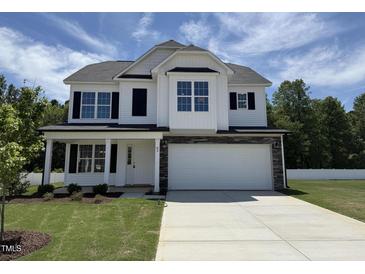 New two-story home with a white facade, black shutters, stone accents, and a spacious two-car garage at 83 W Emily Gardens Dr, Selma, NC 27576
