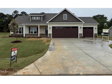 Inviting new construction home with a three-car garage and neatly sodded front lawn at 87 Tee Dr, Selma, NC 27576