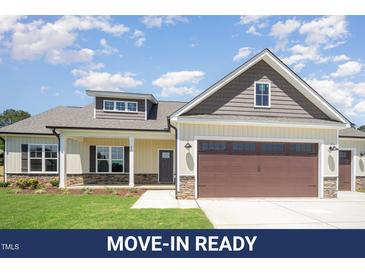 Charming single-Gathering home with a stone-accented facade, two-car garage, and well-manicured lawn at 87 Tee Dr, Selma, NC 27576