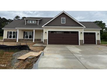 New construction home featuring a two-car garage, stone accents and neutral-colored siding at 87 Tee Dr, Selma, NC 27576