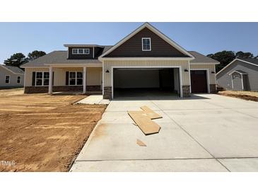 Newly constructed home with a two-car garage and neutral-toned siding accented by stone and dark brown trim at 87 Tee Dr, Selma, NC 27576