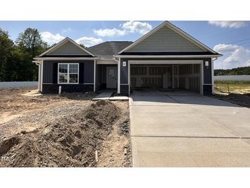 New home featuring a welcoming entrance, an attached two-car garage and a partially landscaped yard at 89 W Emily Gardens Dr, Selma, NC 27576