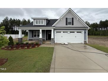 Charming two-story home with landscaped yard, attached garage, and welcoming front porch at 98 Laramie Ln, Selma, NC 27576