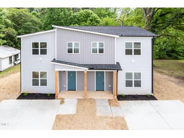 Modern two-story duplex features a gray facade, blue doors, and well-manicured landscaping at 1047 |1049 E Harnett St, Dunn, NC 28334
