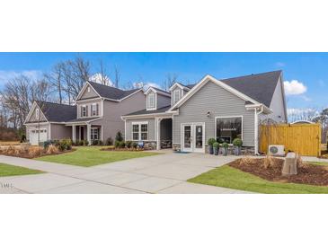 A view of the two-story home with gray siding, dormers, well-manicured lawns, and a concrete driveway at 153 Tennyson Dr # 235, Garner, NC 27529