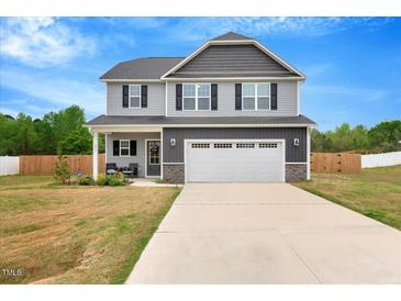 Charming two-story home features a gray facade, inviting front porch, and a two-car garage at 211 Tobacco Barn Dr, Angier, NC 27501