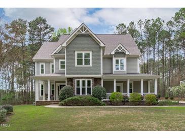 Inviting two-story home featuring a covered porch, stone accents, and beautifully landscaped grounds at 2408 Merion Creek Dr, Apex, NC 27539
