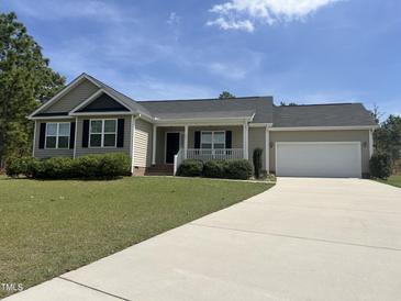 Charming one-story home with a well-manicured lawn and attached garage on a sunny day at 27 Belmont Ct, Lillington, NC 27546
