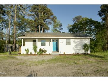 Charming single-story home with a light blue front door, surrounded by trees at 3728 Gideon Dr, Wake Forest, NC 27587