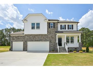 Beautiful two-story home featuring stone and white siding, a three-car garage, and a well-manicured front yard at 420 Shelby Meadow Ln, Angier, NC 27501