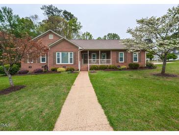 Charming brick home featuring a manicured lawn, inviting front porch, and beautiful landscaping at 422 Old Scarborough Ln, Garner, NC 27529