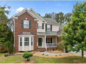 Charming two-story home with a brick and siding exterior, a well-manicured lawn, and a welcoming front porch at 4709 Knights Arm Dr, Durham, NC 27707