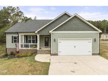 Charming home featuring a covered porch, two-car garage, and nicely landscaped front yard at 52 Sagebrook Ct, Zebulon, NC 27597