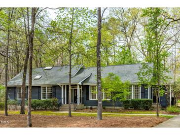 Charming single-story home with gray siding, black shutters, and lush trees at 706 Kensington Dr, Chapel Hill, NC 27514