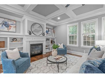 Bright living room featuring a cozy fireplace, built-in shelves, and coffered ceiling at 1104 Hobson Ct, Raleigh, NC 27607