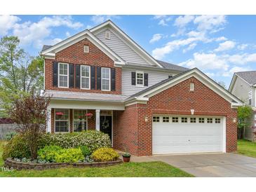 Charming two-story brick home with a well-maintained lawn, attached two car garage, and manicured landscaping at 112 Mendells Dr, Holly Springs, NC 27540