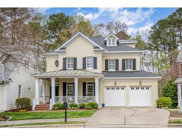 Charming yellow brick two-story home with black shutters, a covered front porch, and an attached two-car garage at 119 Faison Rd, Chapel Hill, NC 27517