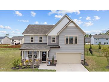 Charming two-story home featuring a manicured lawn, attached two-car garage, and a welcoming front porch at 2157 Blue Iris Way, Zebulon, NC 27597