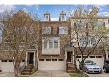 Beautiful brick townhome featuring an attached garage, a small portico, and tasteful landscaping at 452 Panorama Park Pl, Cary, NC 27519