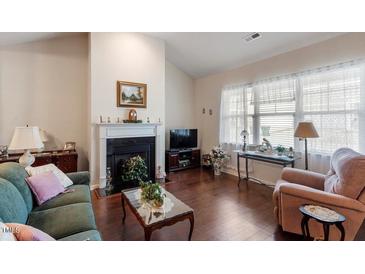 Cozy living room boasts a fireplace, hardwood floors, and lots of natural light from bright windows at 4712 Bright Pebble Ct, Raleigh, NC 27604