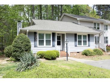 Charming townhome with blue siding, black shutters, landscaped lawn and brick steps at 6417 Meadow View Dr, Raleigh, NC 27609