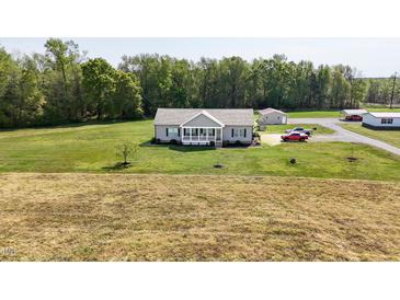 Charming single-story home with a welcoming front porch and a spacious green lawn surrounded by trees at 8079 Stone Heritage Rd, Middlesex, NC 27557