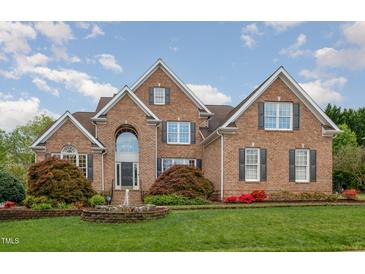 Traditional brick home with a manicured lawn, fountain, and beautiful landscaping at 9201 Club Hill Dr, Raleigh, NC 27617