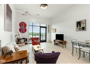 Bright living room featuring large windows with a view, modern decor, and light wood flooring at 120 Mosaic Blvd # 308, Pittsboro, NC 27312