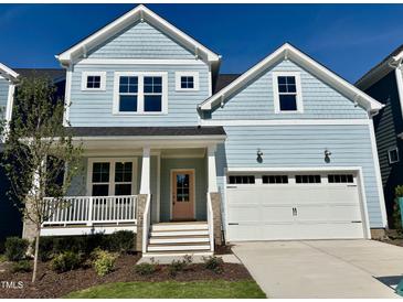 Charming two-story home with pale blue siding, white trim, a pink front door and attached two-car garage at 1237 Porters Call Dr, Wendell, NC 27591