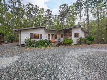 Charming single-story home featuring stone accents, gravel driveway, and lush landscaping at 1604 Meadow Ln, Chapel Hill, NC 27516