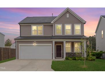 Charming two-story home with a two-car garage, stone accents, and a well-manicured lawn during a lovely dusk at 205 Loxton St, Fuquay Varina, NC 27526