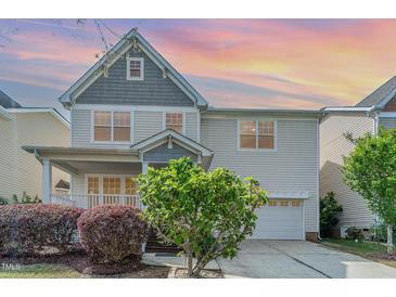 Charming two-story home featuring a welcoming porch, landscaped yard and attached garage at sunset at 3047 Kilarney Ridge Loop, Cary, NC 27511