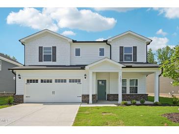Charming two-story home with a two car garage, landscaped yard, and inviting covered front porch at 3841 Rosebush Dr, Zebulon, NC 27597
