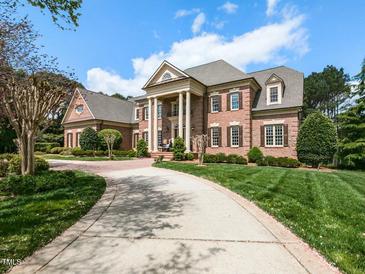 Stately brick home with grand columns, a circular driveway, and a well-manicured lawn at 5768 Cavanaugh Dr, Raleigh, NC 27614