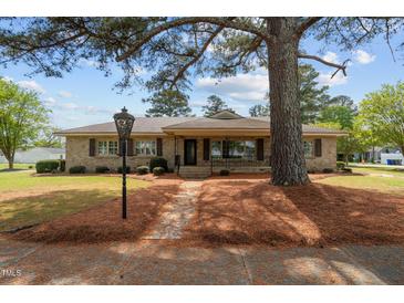 Charming single-story home with stone facade, mature landscaping, and inviting front porch at 609 W Main St, Benson, NC 27504