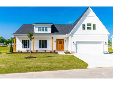 Charming two-story home with a well-manicured lawn, wood accents, and classic architectural details at 95 Watermeadow Dr, Clayton, NC 27520